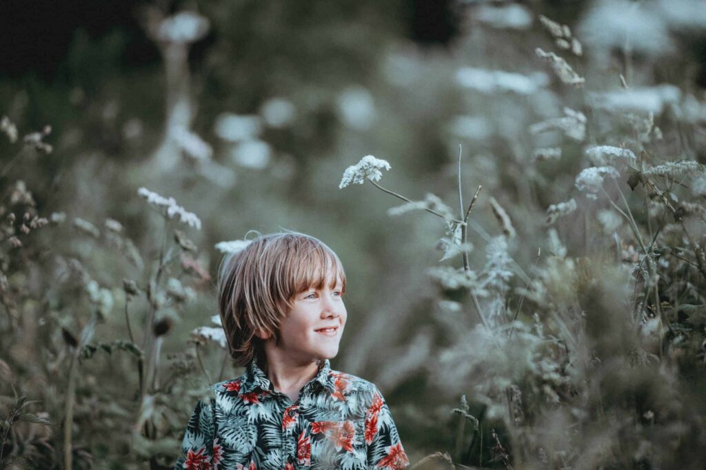A smiling young boy with light brown hair and a floral shirt stands among tall, white wildflowers, reflecting the joy and peace of a job well done. At Bell Brothers, our trusted technicians bring the same care to your home—each team member is background-checked for your peace of mind, provides upfront pricing with no surprise fees thanks to our No Surprise Guarantee, and proudly serves communities all across Northern California.