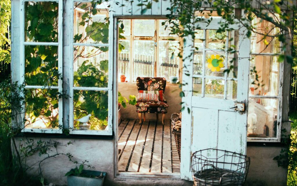 A welcoming, sunlit greenhouse with open windows and door showcases a floral armchair and vibrant potted plants inside. Just like the inviting scene, Bell Brothers is dedicated to bringing comfort to your home with our No Surprise Guarantee, professional background-checked technicians, and honest upfront pricing. Proudly serving Northern California communities with trusted service and a reputation you can count on.
