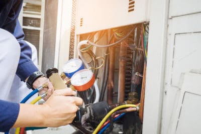 A Bell Brothers technician—background-checked for your peace of mind—uses a manifold gauge to expertly inspect and service an air conditioning unit’s refrigerant system. Our trusted team proudly upholds our No Surprise Guarantee with honest, upfront pricing and decades of dependable service throughout Northern California communities.