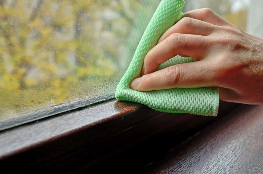 A Bell Brothers technician, fully background-checked and trusted throughout Northern California, wipes condensation from a window with a green cloth. With our No Surprise Guarantee and clear, upfront pricing, you can count on reliable service and peace of mind every step of the way.