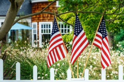 Three American flags stand proudly behind a classic white picket fence, with a welcoming home and garden in the background—symbolizing the trusted service Bell Brothers brings to Northern California communities. Our No Surprise Guarantee ensures upfront pricing with no hidden fees, and all of our technicians are background-checked for your peace of mind. That’s part of why homeowners across the region count on Bell Brothers for honest, reliable service every time.