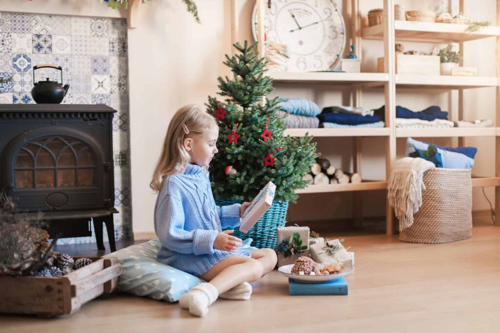 A young girl in a blue sweater sits on a cushion beside a beautifully decorated Christmas tree, surrounded by holiday decorations and gifts in a warm, inviting room. Just like the joy and comfort of the holidays, Bell Brothers brings trusted service to homes across Northern California. With their No Surprise Guarantee, background-checked technicians, and upfront pricing, families can count on Bell Brothers for reliable care—earning a strong reputation throughout the community.