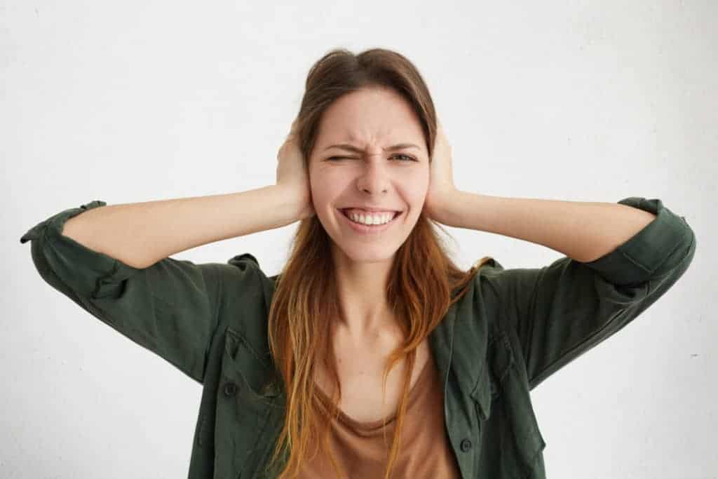 A smiling woman with long brown hair covers her ears, standing against a plain white background. At Bell Brothers, we’re proud to offer service you can trust—including our No Surprise Guarantee, upfront pricing with no hidden fees, and experienced technicians who are thoroughly background-checked. That’s why families across Northern California rely on us for comfort and peace of mind.