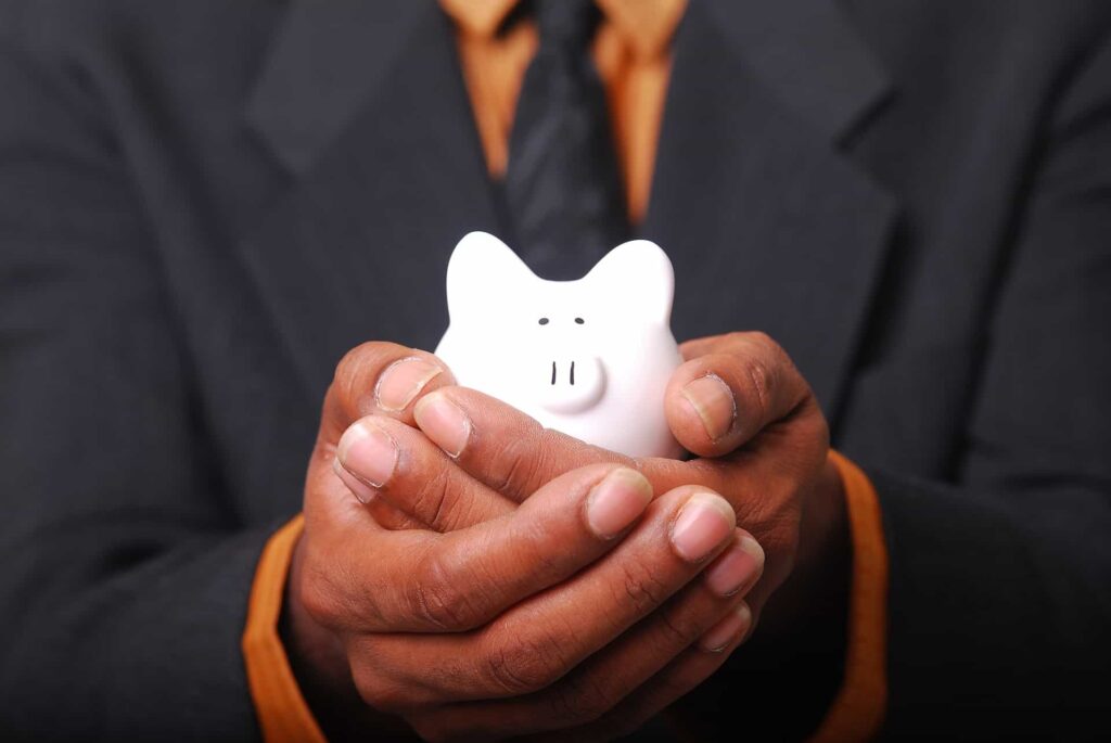 A person in a suit gently holds a white piggy bank, representing the financial peace of mind that Bell Brothers provides. Through our No Surprise Guarantee, background-checked technicians, and honest, upfront pricing, we deliver trusted service to families across Northern California communities.