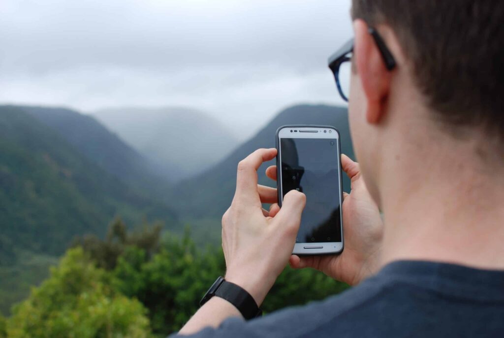 A person wearing glasses and a smartwatch captures a photo of a misty mountain view with their smartphone, reflecting the peace of mind you can expect from Bell Brothers. Trusted across Northern California, Bell Brothers is known for our No Surprise Guarantee, background-checked technicians, transparent upfront pricing, and long-standing reputation for outstanding service in our local communities.