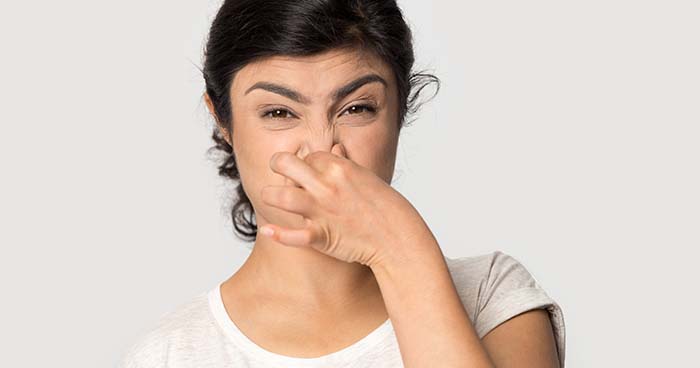 Image: a woman plugging her nose. If you smell sewage in your home, it might be time to consider hydro jetting.