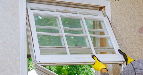 Image: a person installing a double hung window.